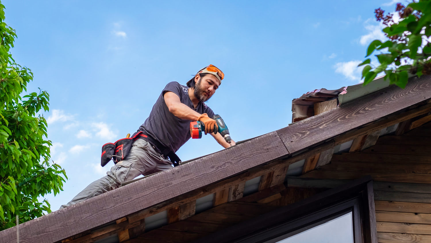 Man working on roof using electric screwdriver