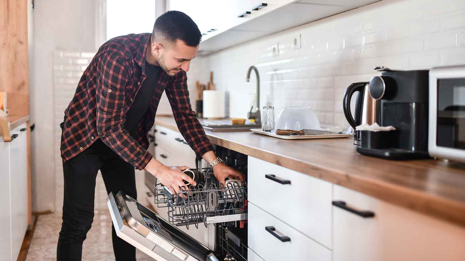 Man arranging dishes in the dishwasher at home
