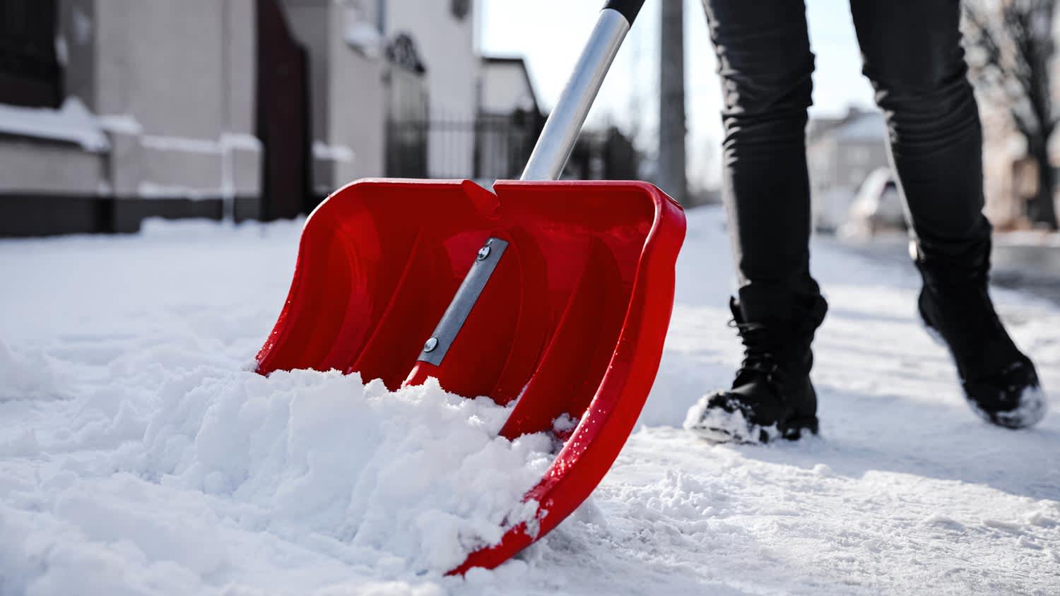 close up of someone shoveling snow in front of home