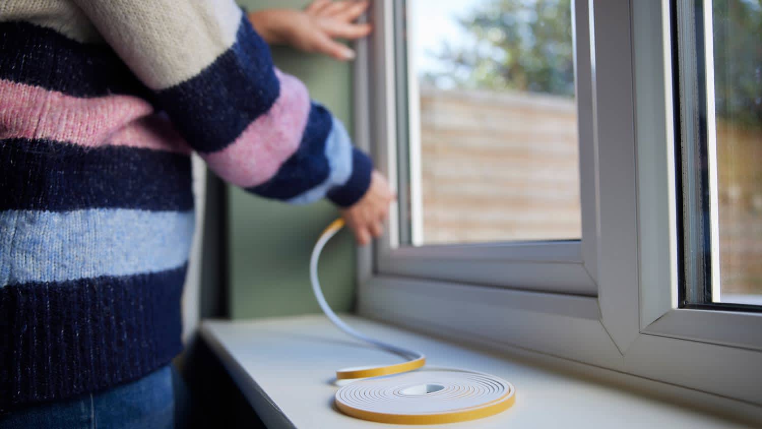 woman insulating window with tape