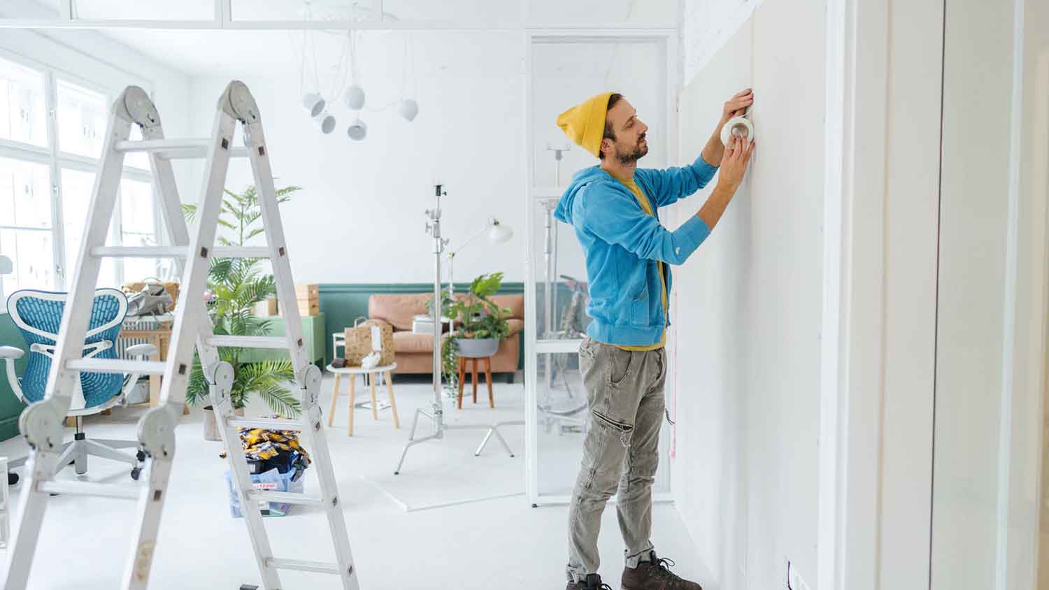 Man using drywall tape to install drywall in his apartment