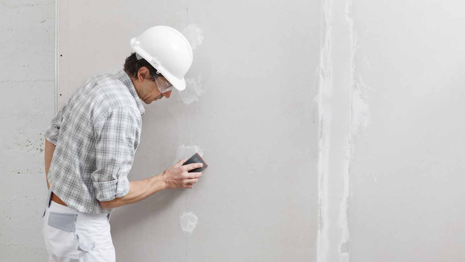 Man sanding and smoothing a plasterboard