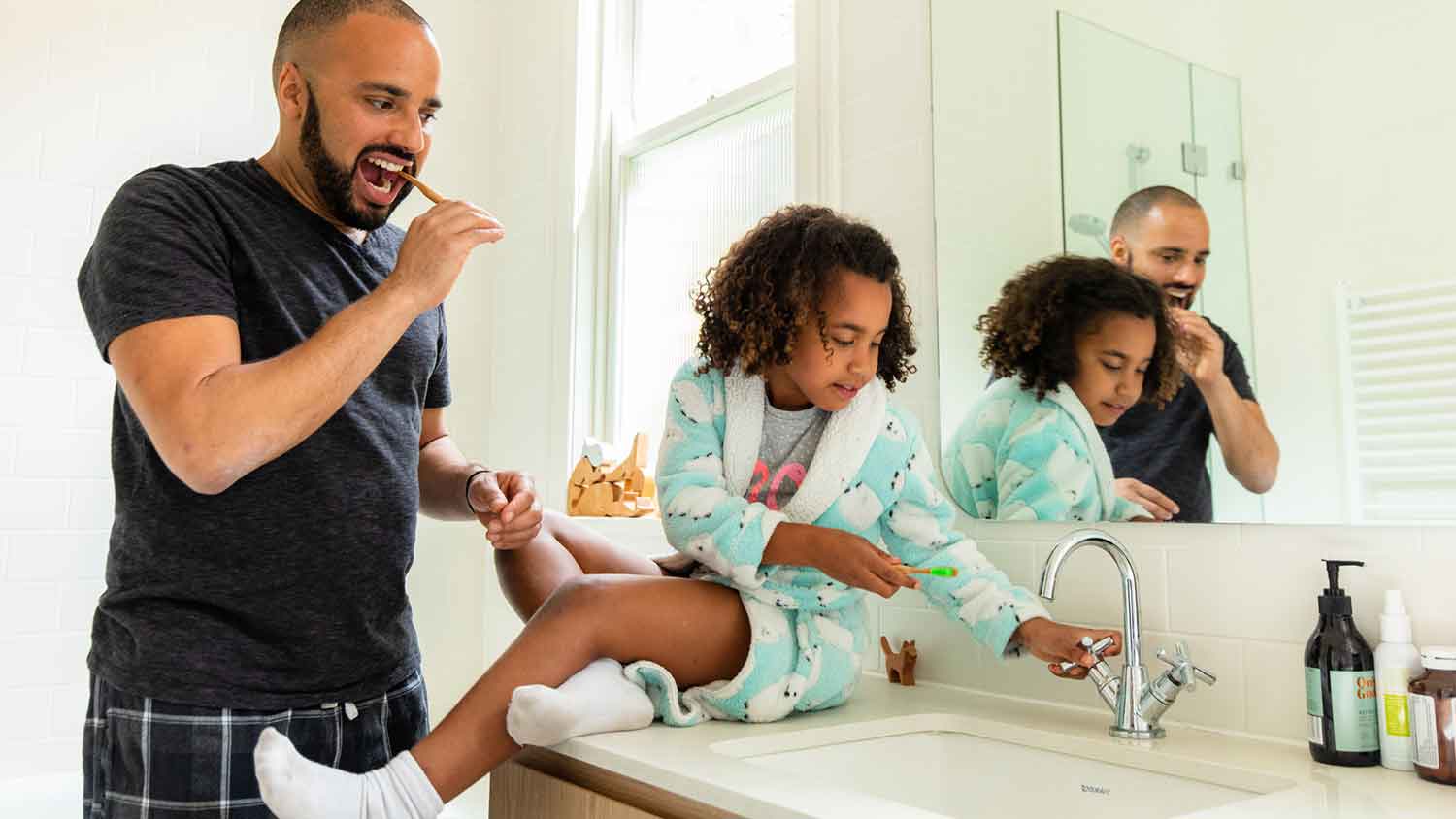 Father and daughter brushing teeth in the morning