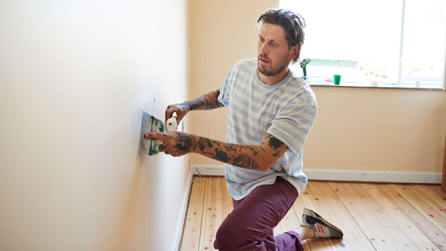 Man skimming wall while renovating home