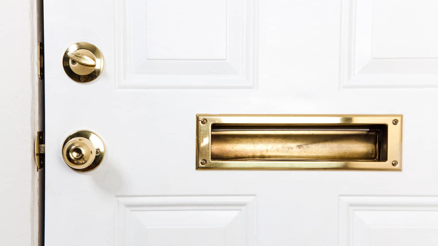 A front door with a door knob, a mail slot and deadbolt lock