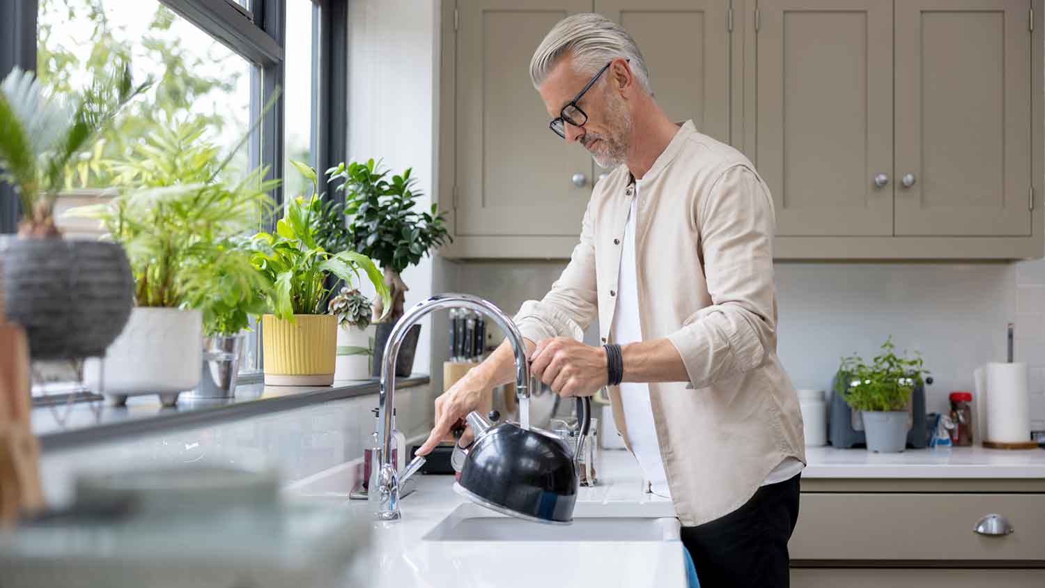 Man filling up kettle in the sink