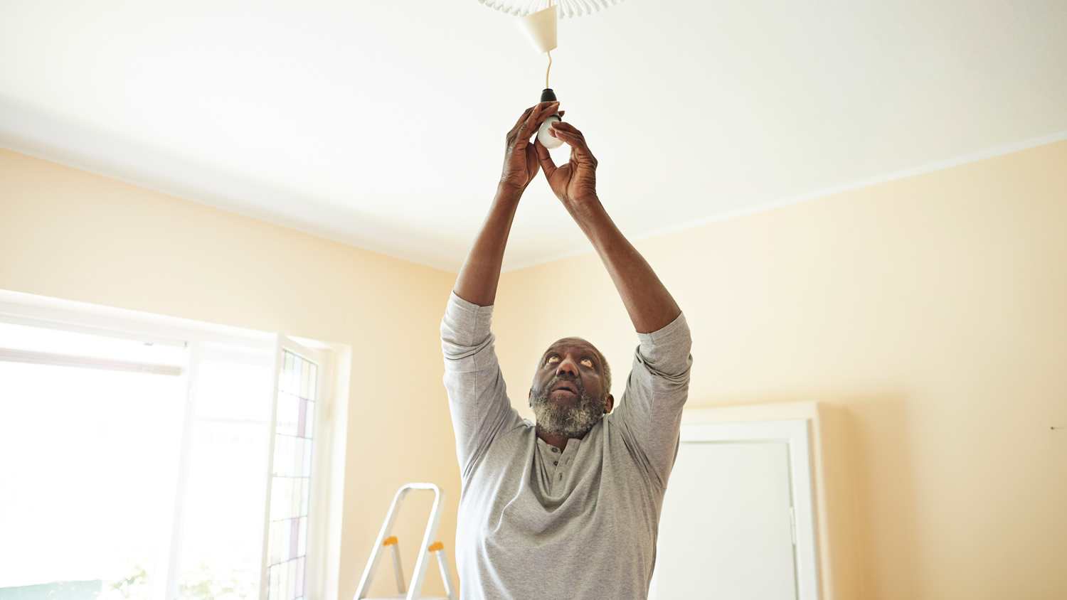 Man changing light bulb while renovating home
