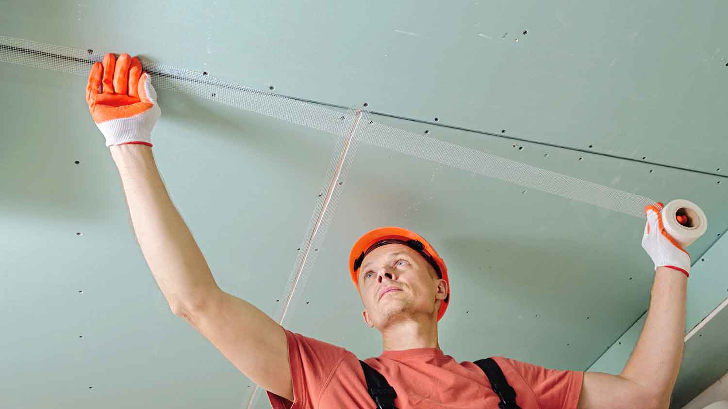 Worker applying mesh drywall tape