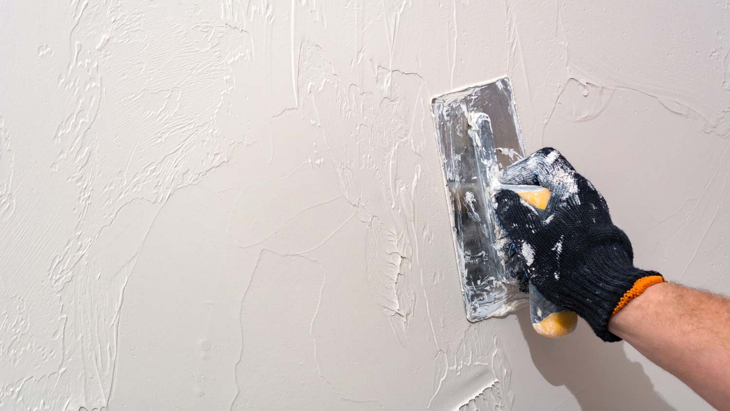 A person applying lime plaster on wall