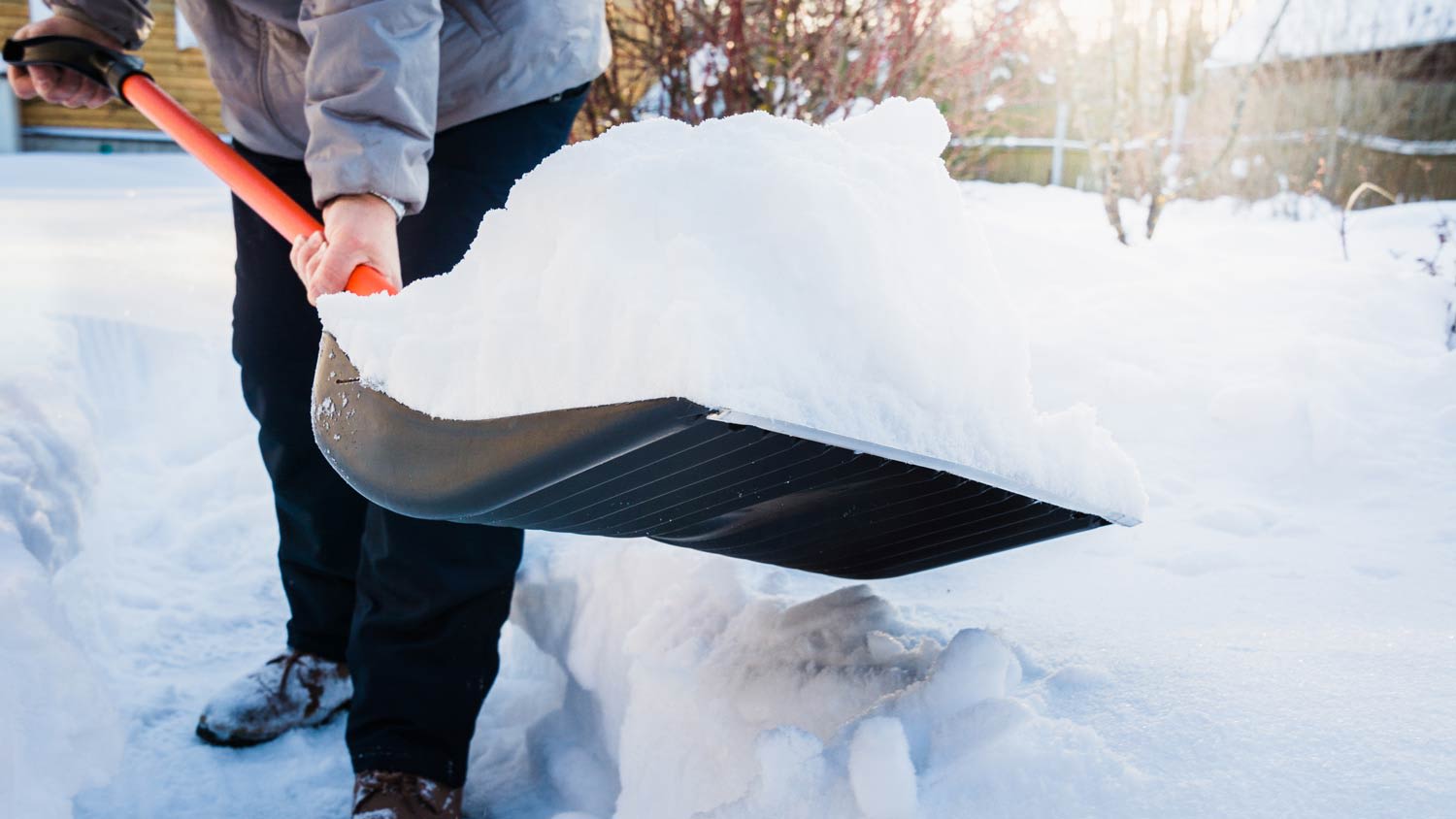 man using his knees to shovel snow