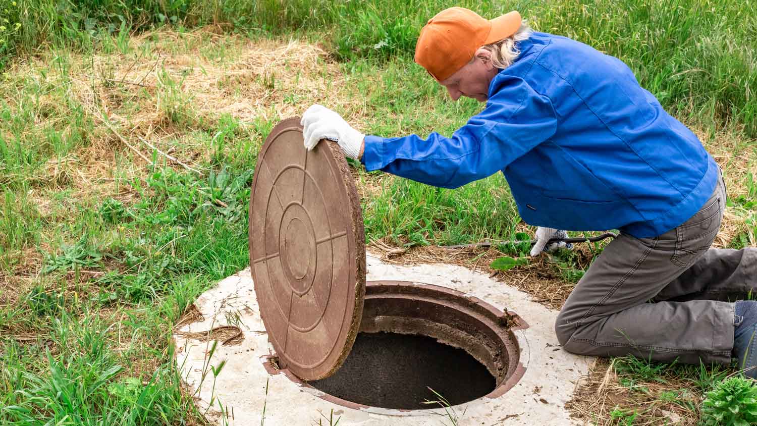 A man using gloves opening a septic tank