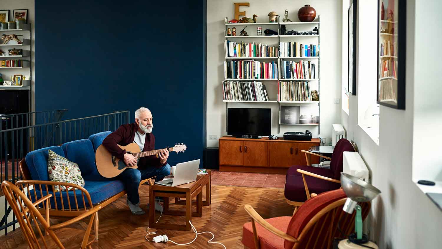 Man taking virtual guitar lessons at home