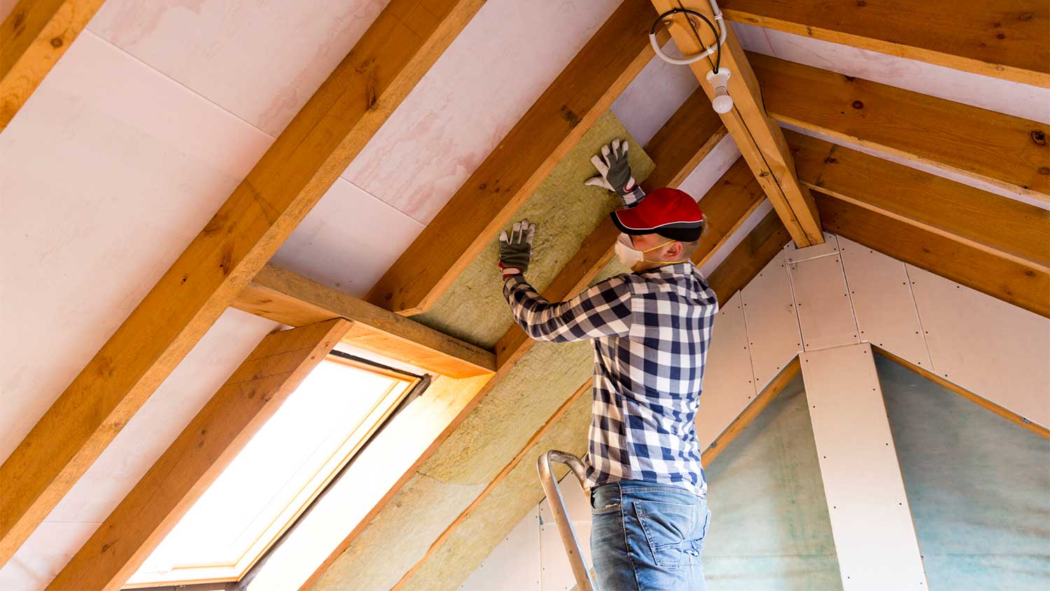 Man installing roof insulation in attic