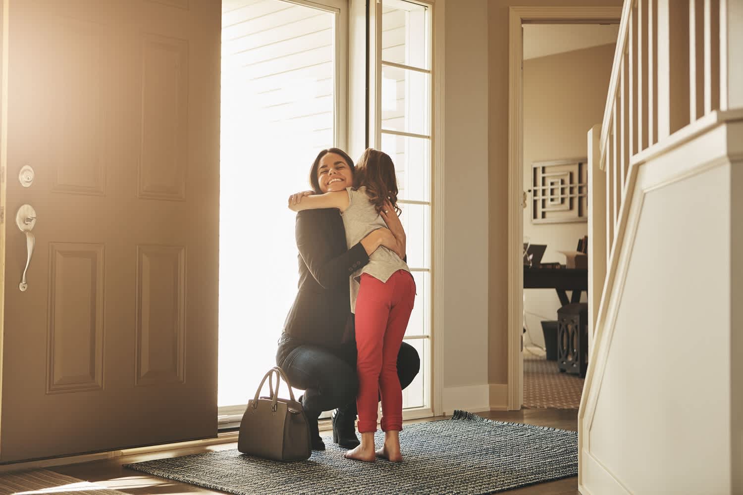 Woman greets little girl at front door