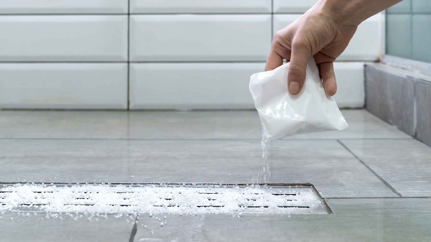 Hand pouring commercial drain cleaner in the shower drain