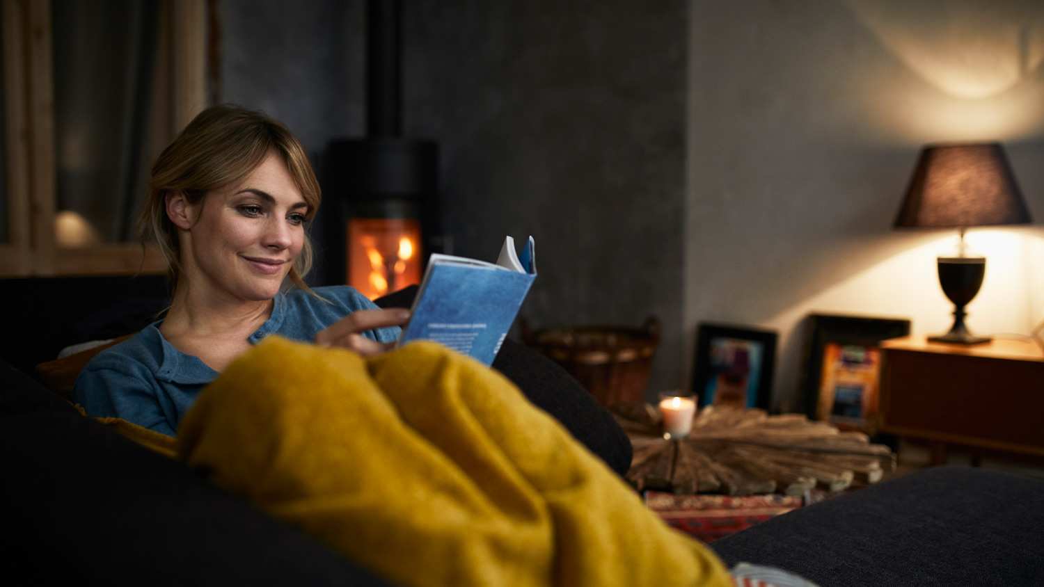 A woman reading a book on couch at her home