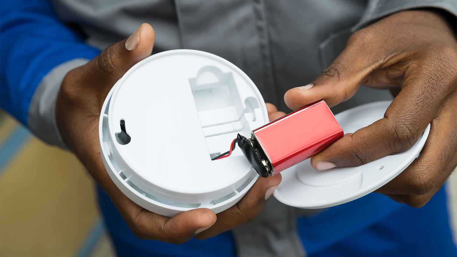 A man replaces the battery in a smoke detector