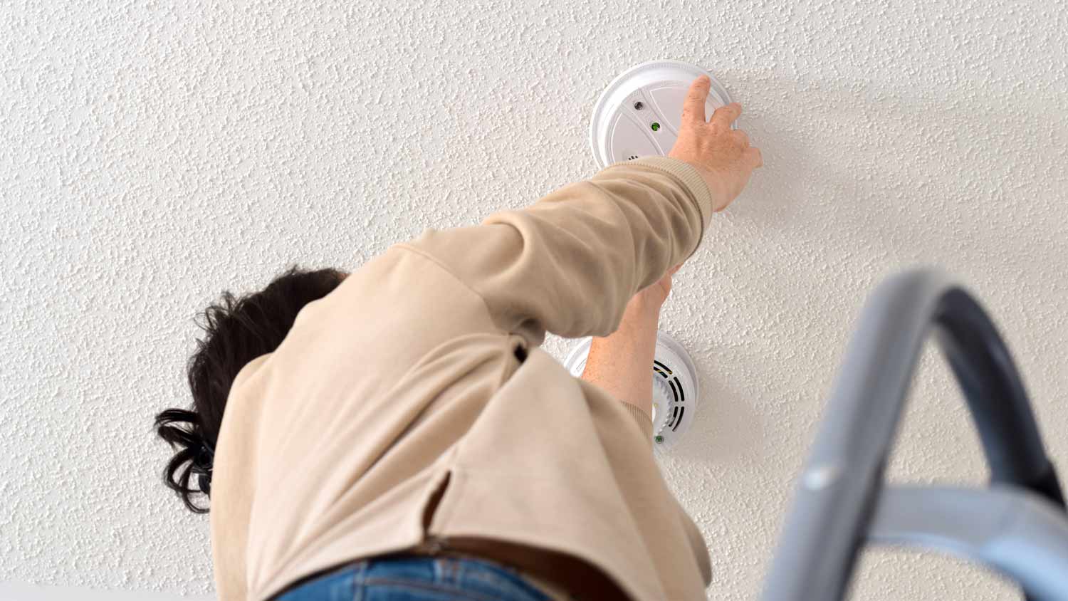 woman changing battery to smoke detector