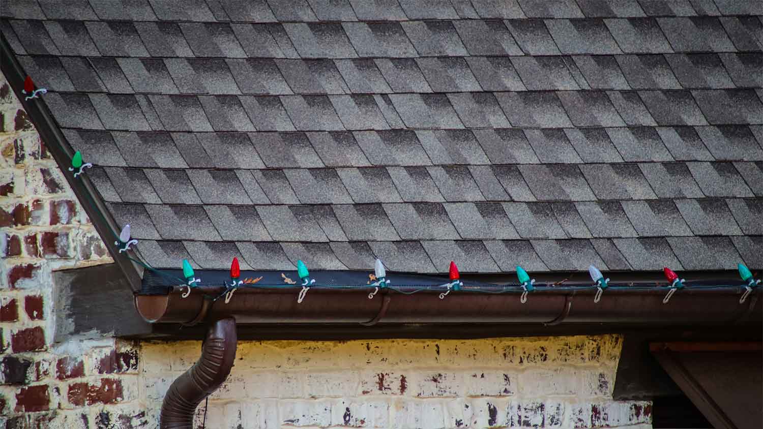 A view of christmas lights hanging on shingle tabs