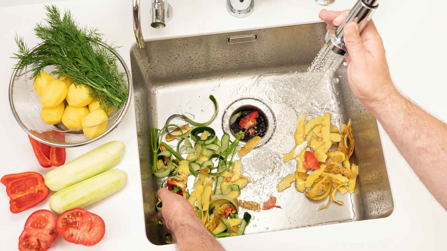 A man throwing food waste in a garbage disposal