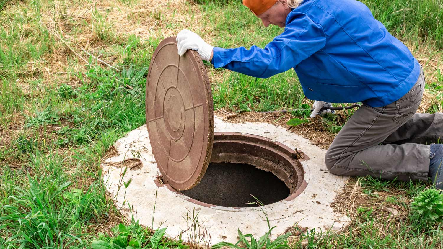 The man opened the cover of the sewer manhole to pump out the sewage