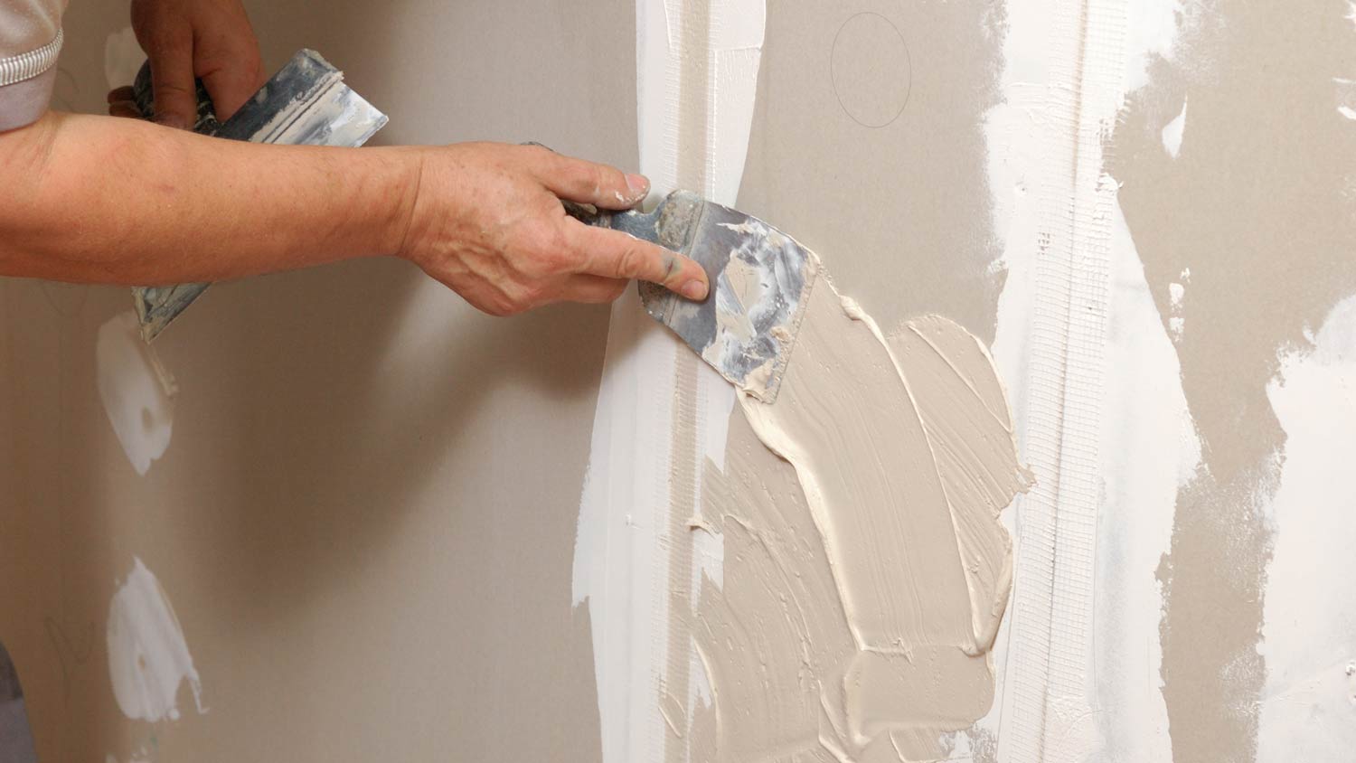 man spreading hot mud on wall