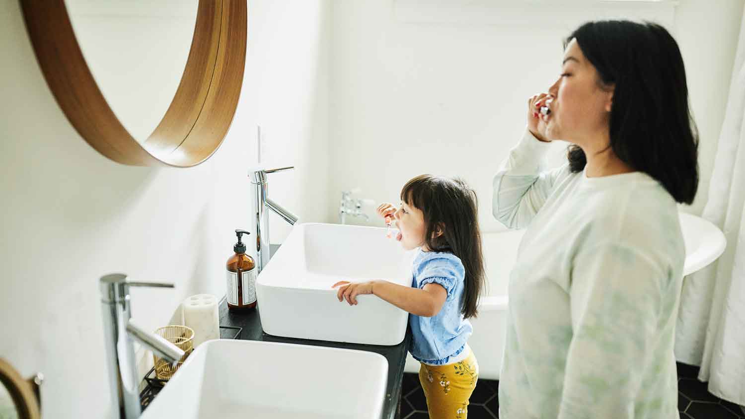 Mother and daughter brushing teeth in the morning