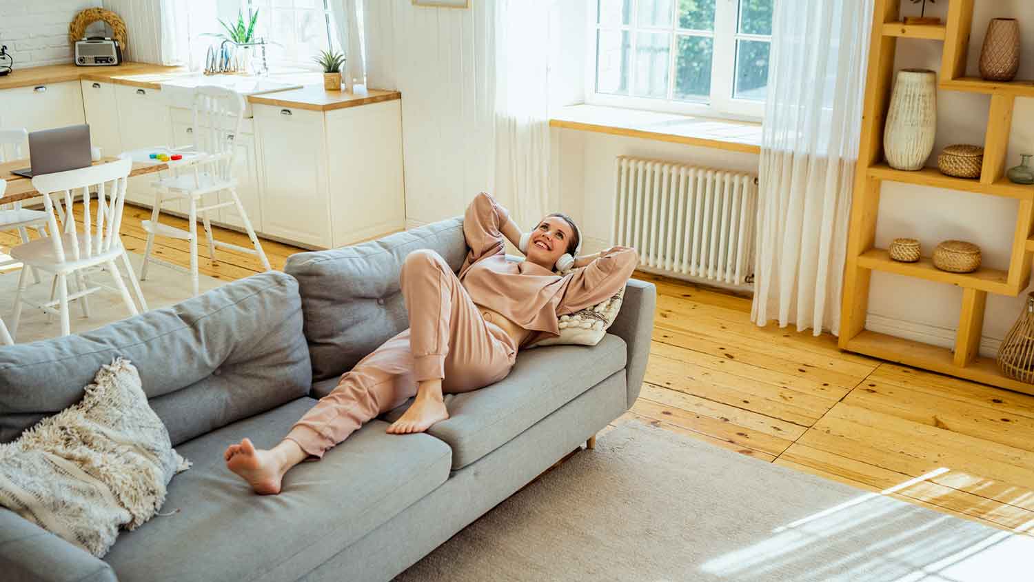 Smiling woman wearing headphones lying on the couch