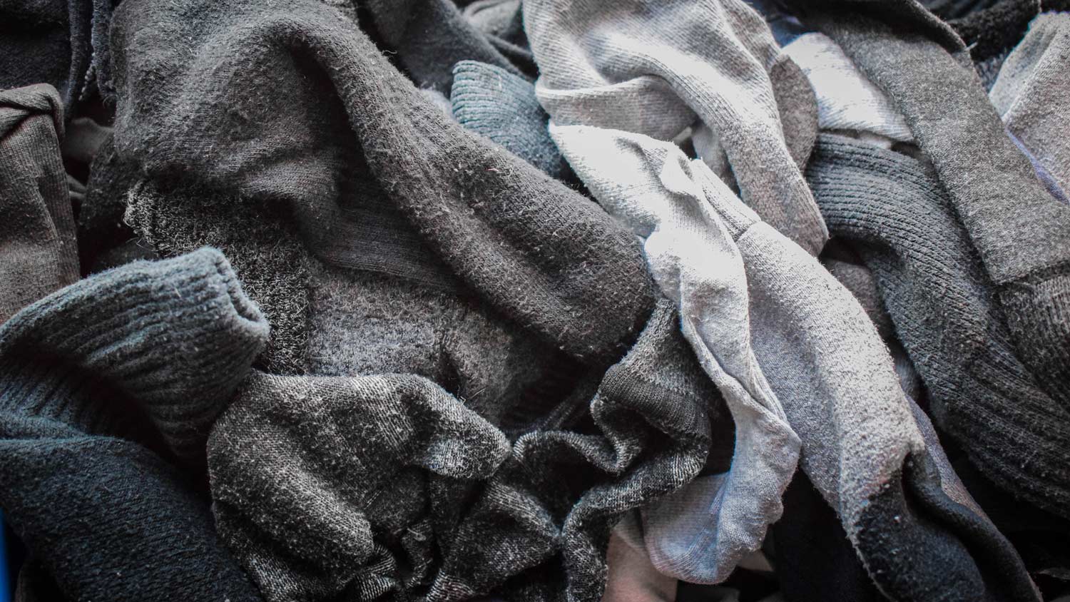 A heap of mismatched socks in different colors and textiles