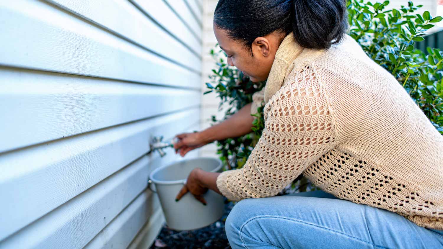 Woman opening outdoor faucet