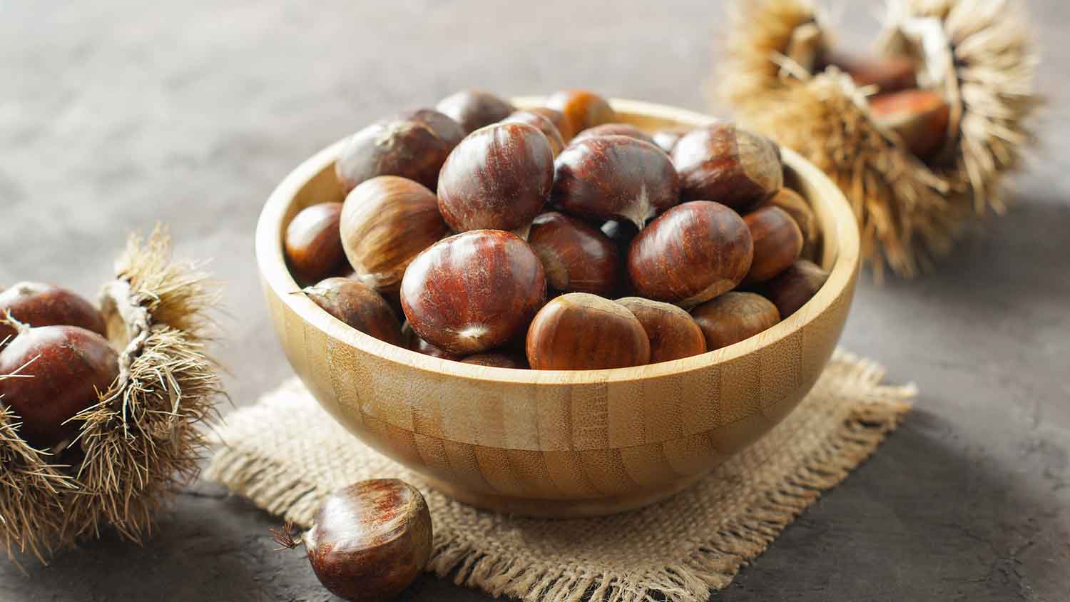 Wooden bowl with fresh raw chestnuts