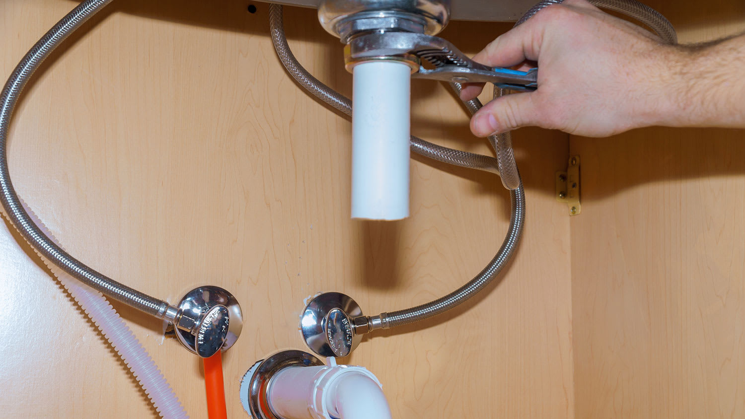 Plumber connecting drain pipe to the kitchen sink