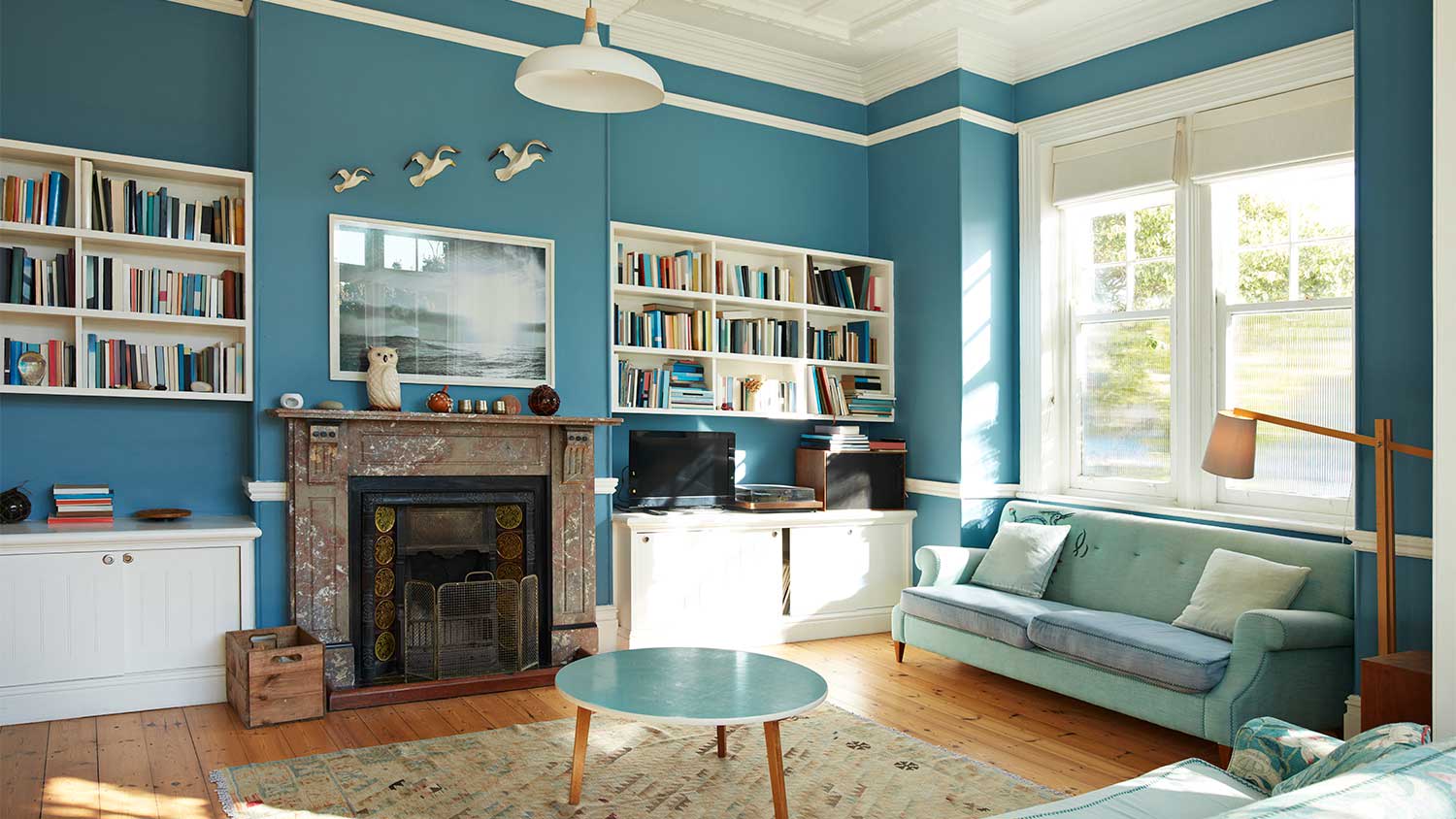 A view of a sunny living room with blue walls