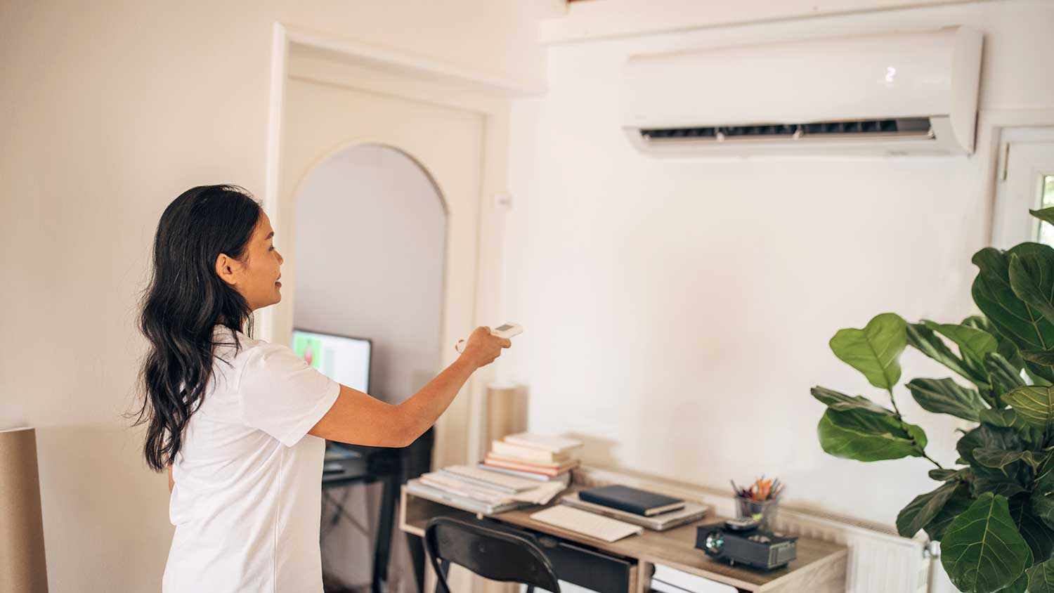 Woman using remote control to turn on mini split ac