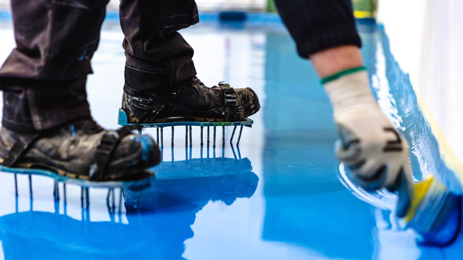 Man applying blue epoxy to floor