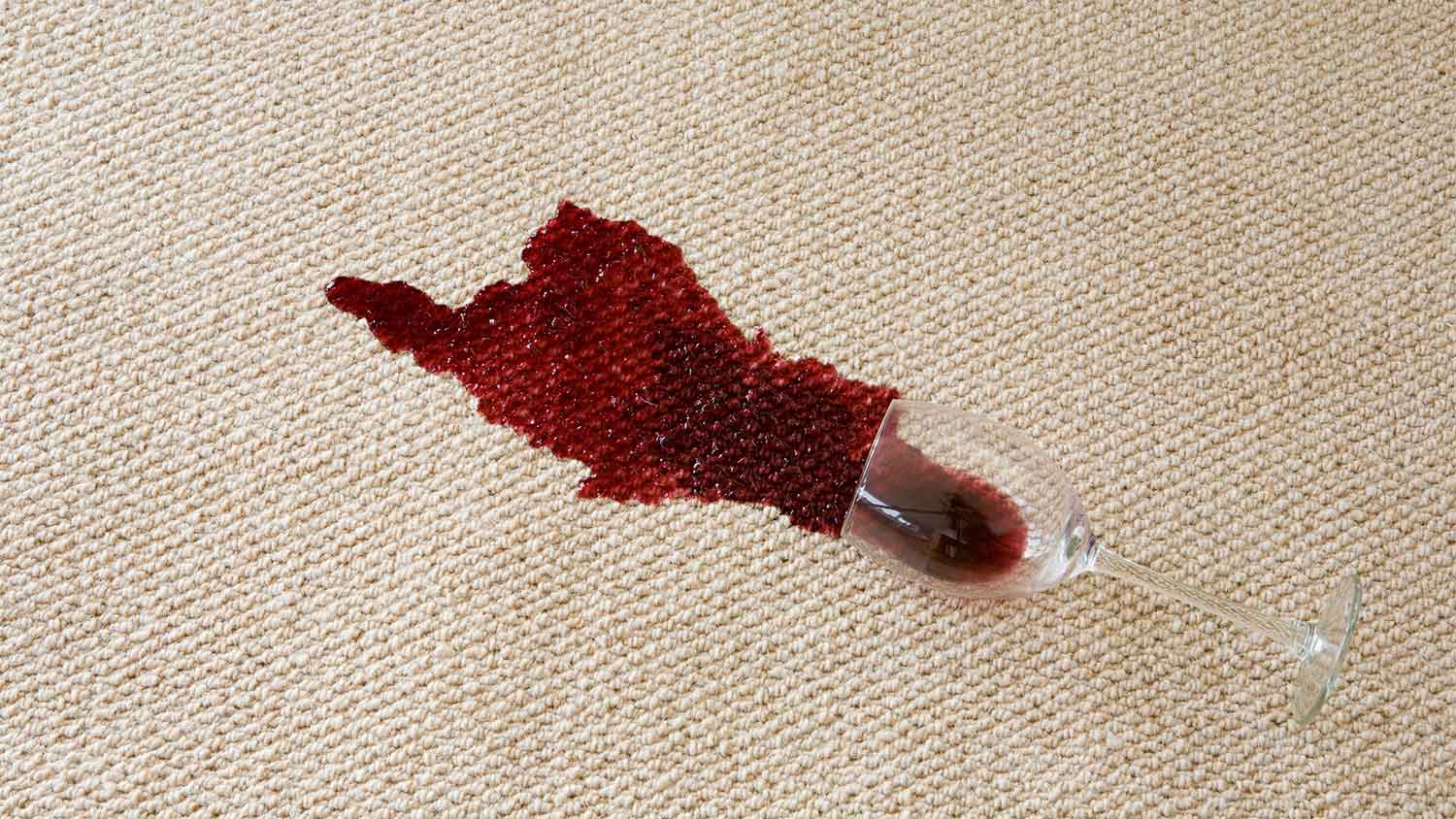 glass with red wine spilled on carpet