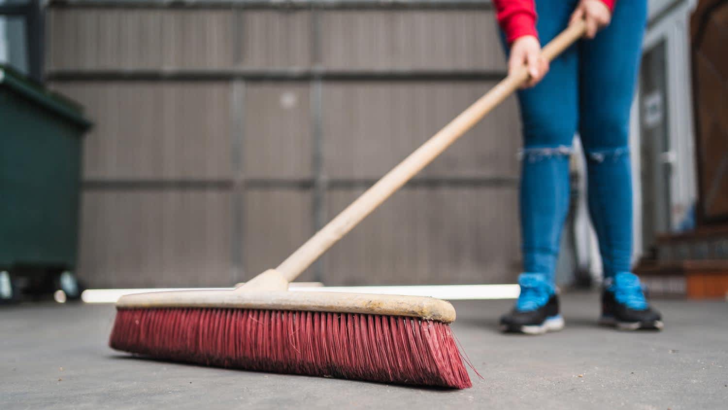 woman using broom in the garage