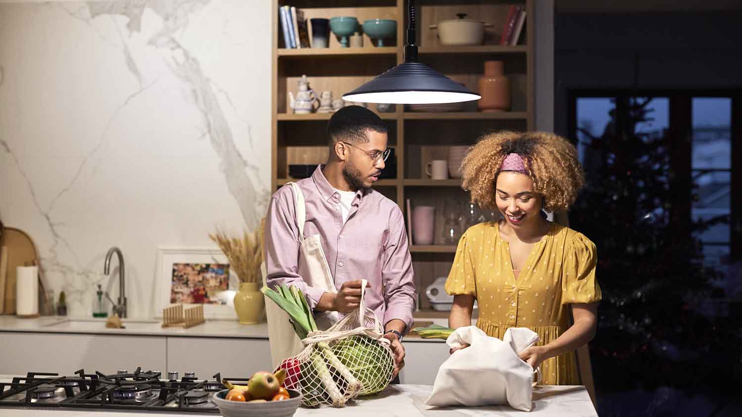 Couple in the kitchen taking veggies out of grocery bags