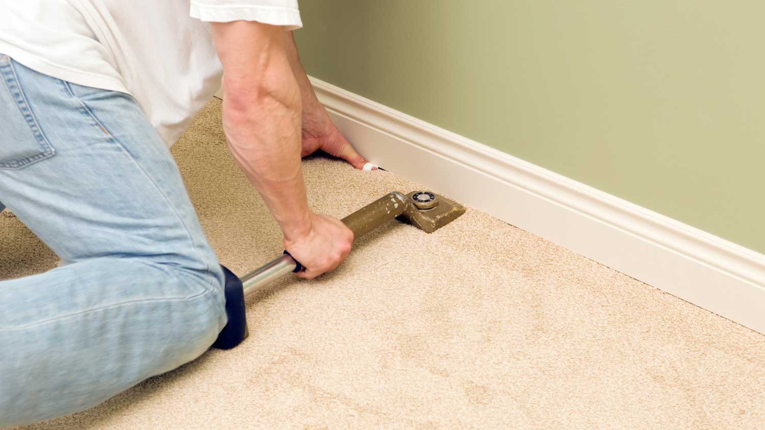 A man installing a carpet in a room