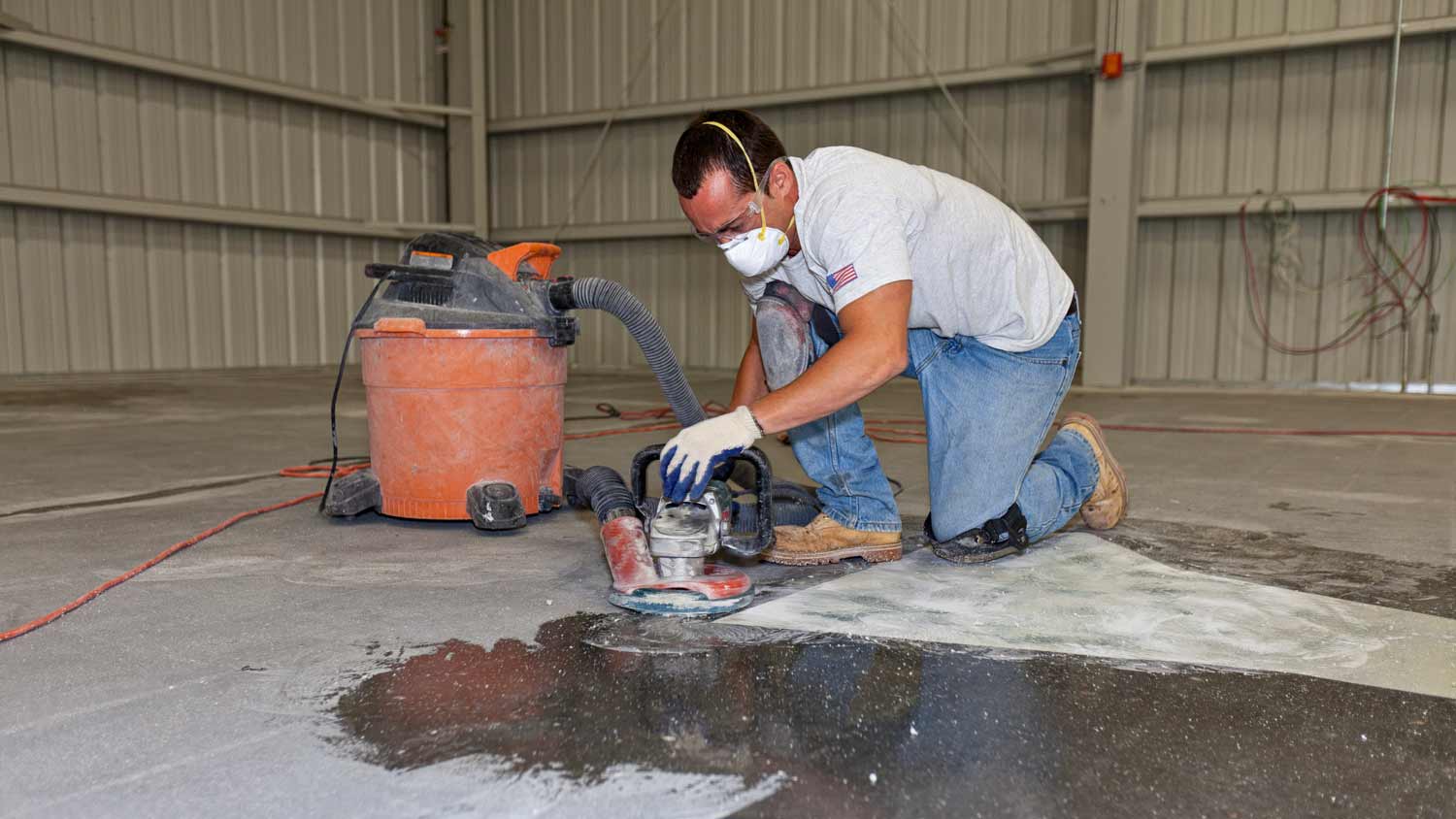 man using sander on concrete garage