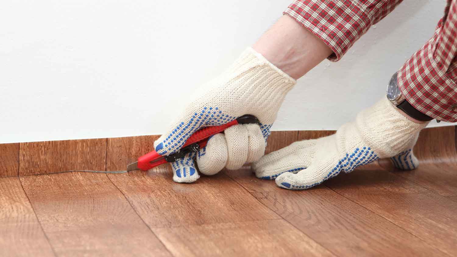 Worker using utility knife to cut sheet vinyl flooring