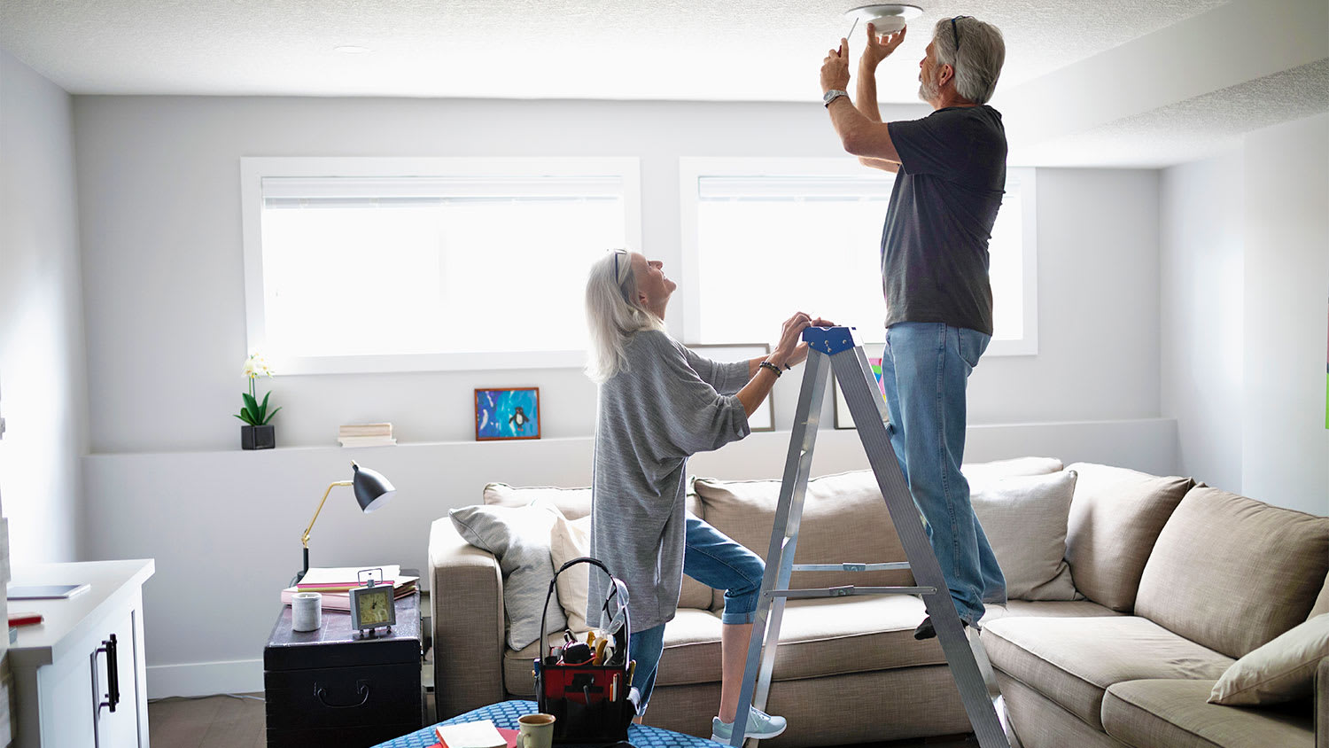 couple replacing smoke detector in living room