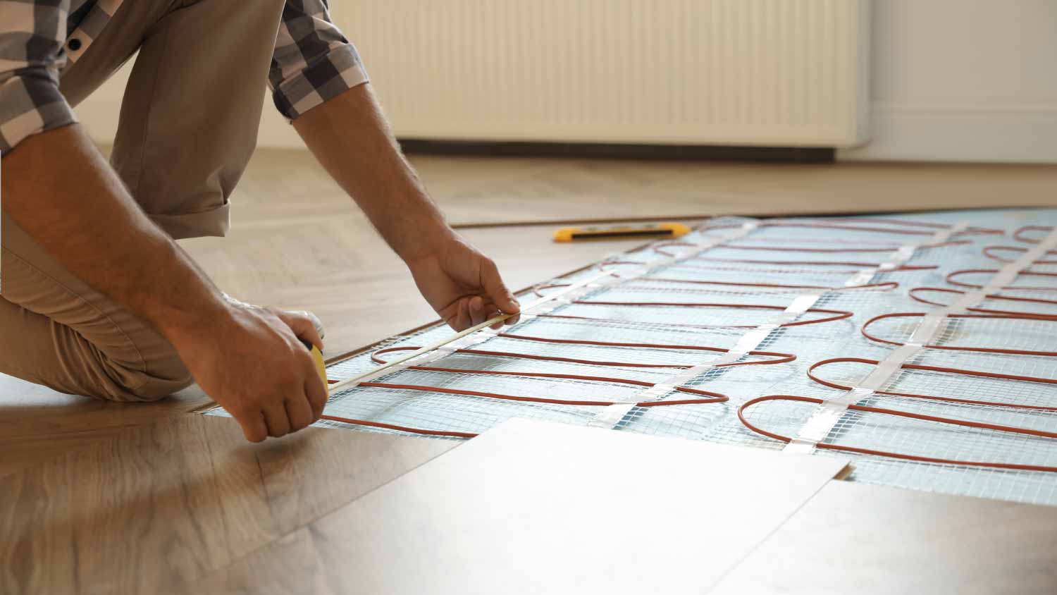 Worker installing electric underfloor heating