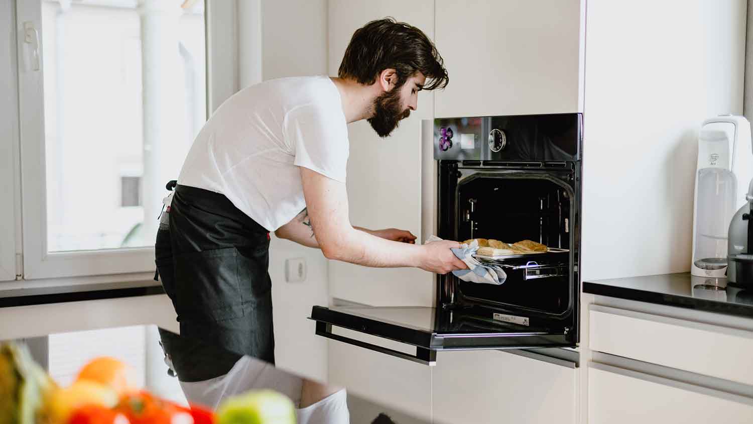 Young man baking pastries in the oven