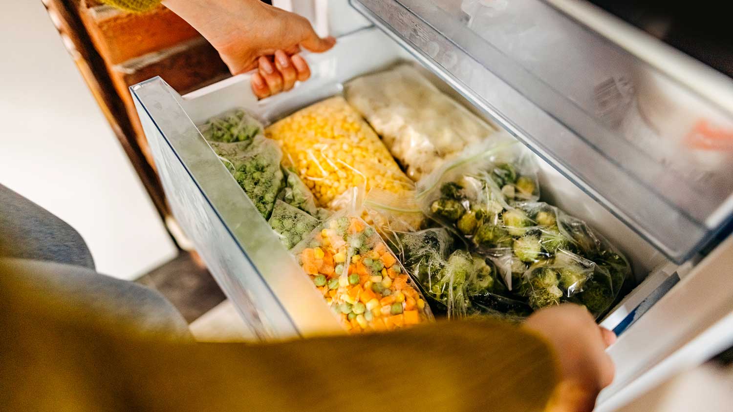 A woman opening a freezer drawer
