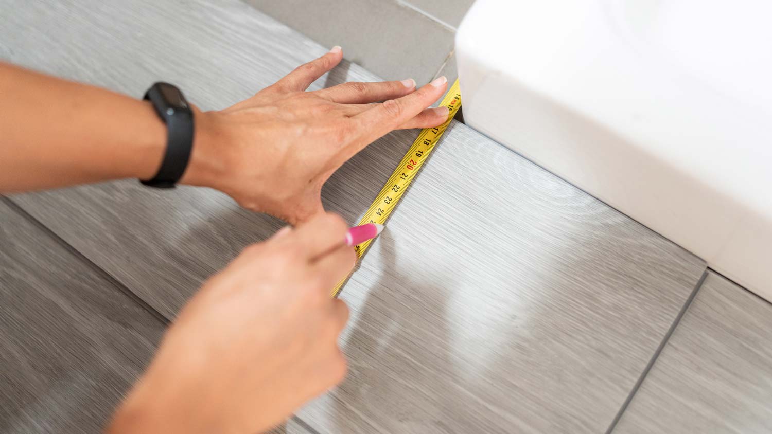 A woman measuring a laminate plank