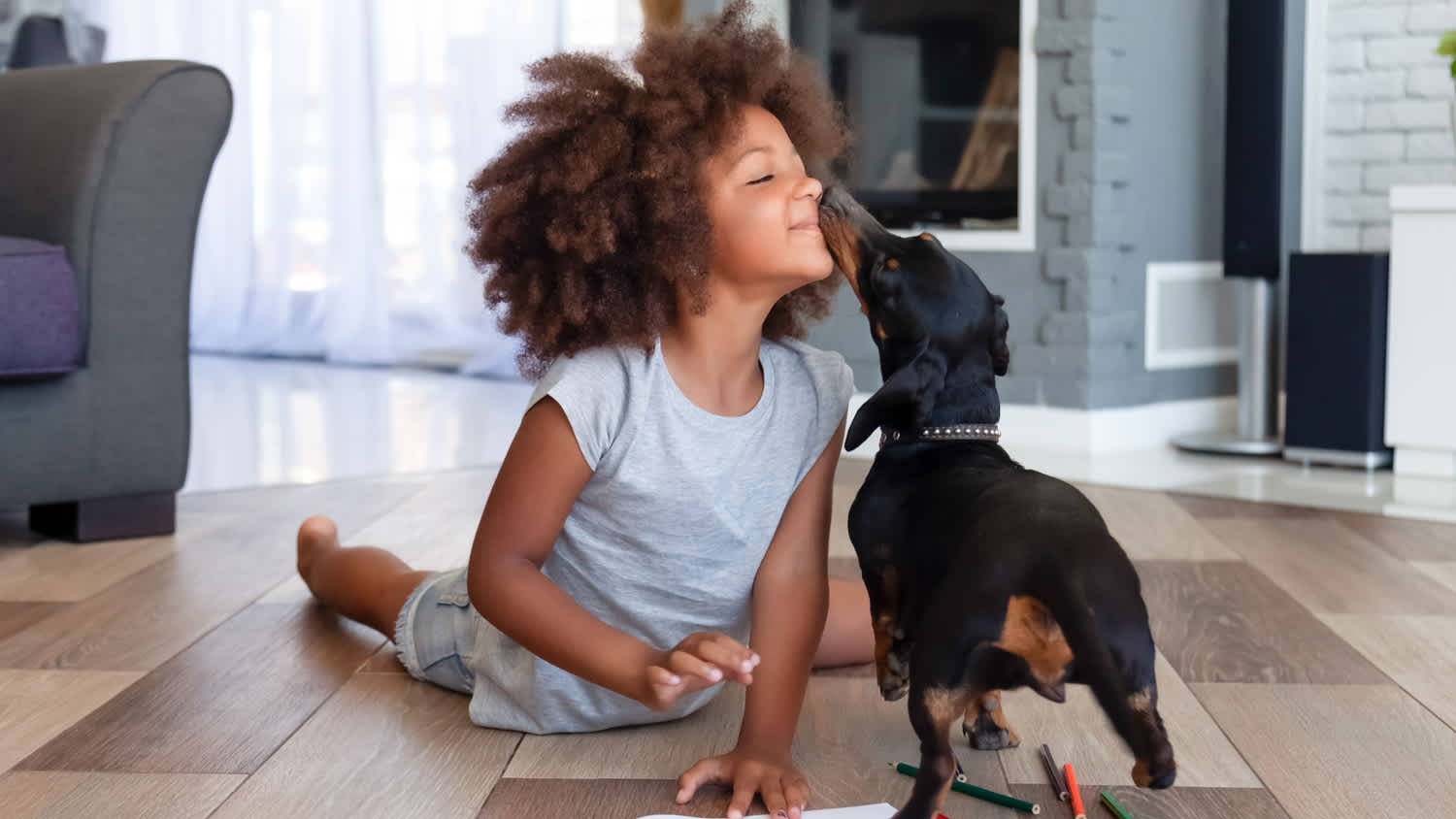 Cute little girl lying on floor playing with dog