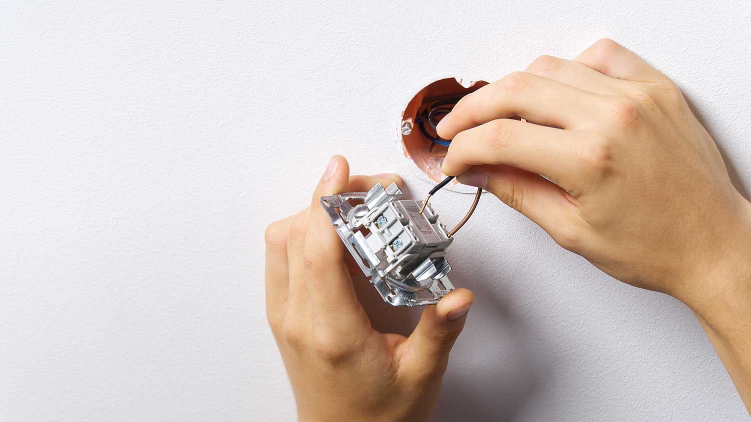 A person wiring a light switch