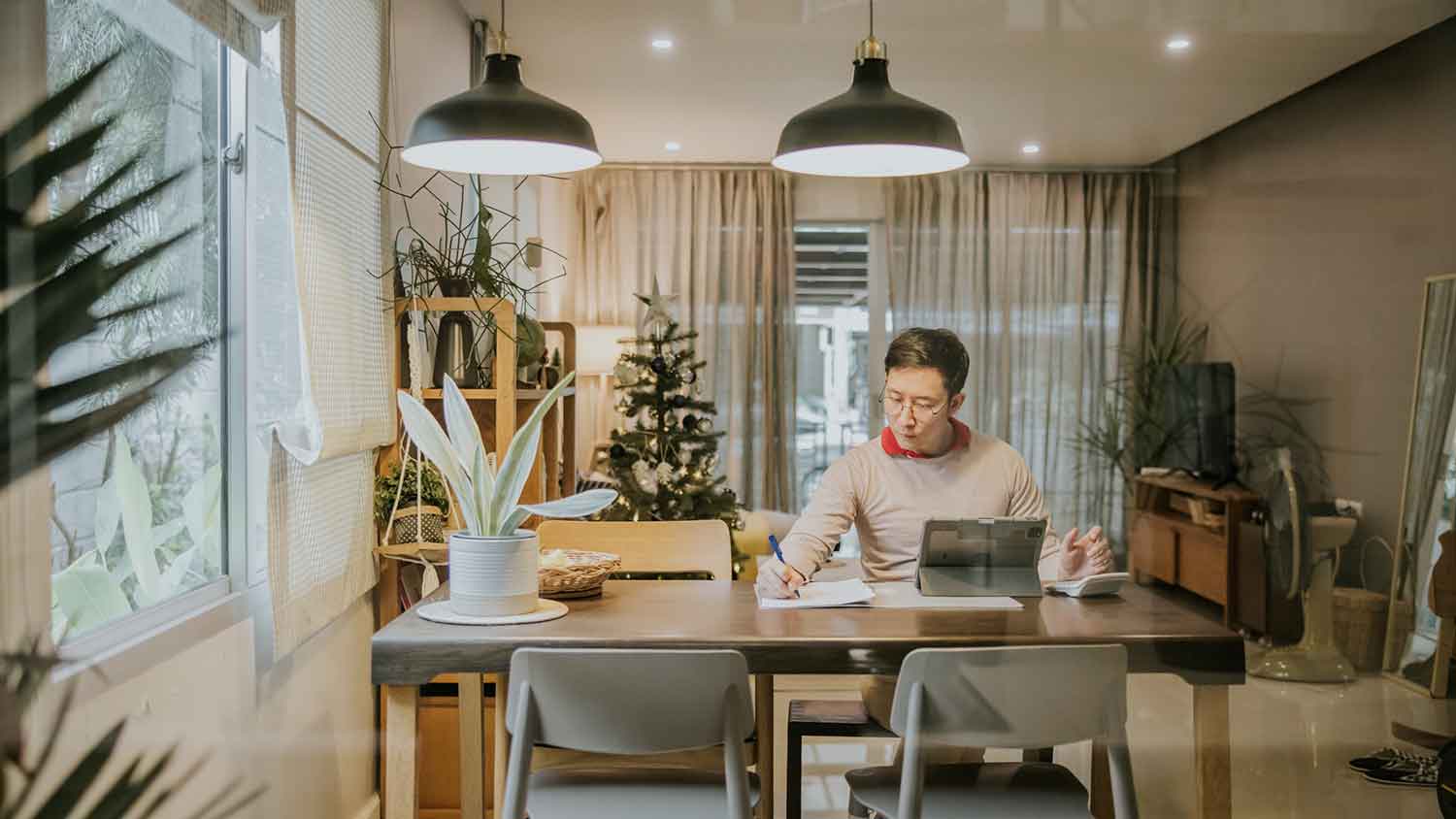 Man in the dining room taking notes and using tablet