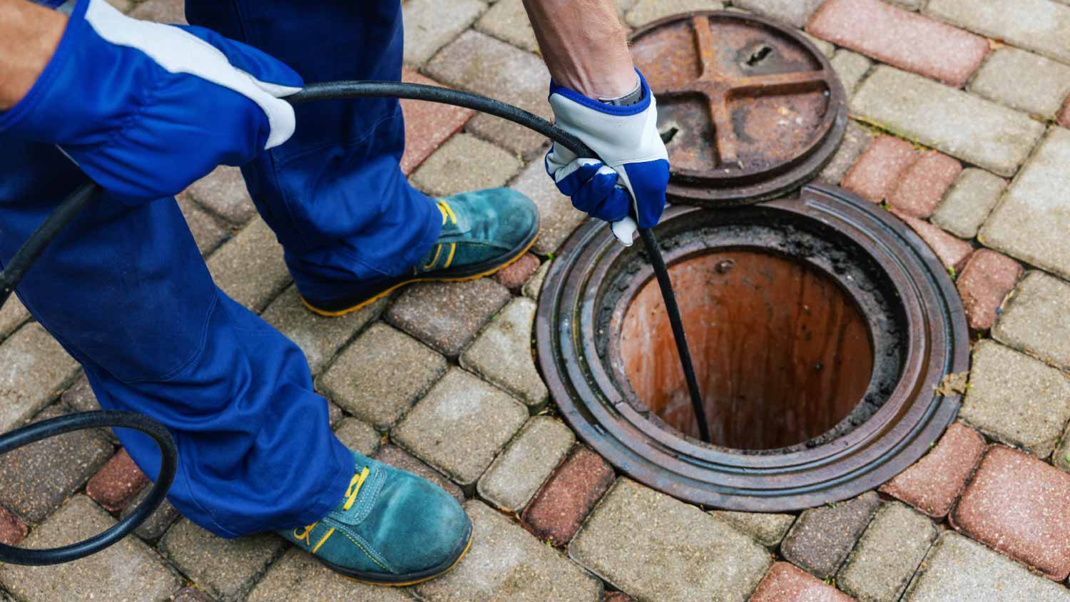 Worker cleaning a clogged drainage with hydro jetting